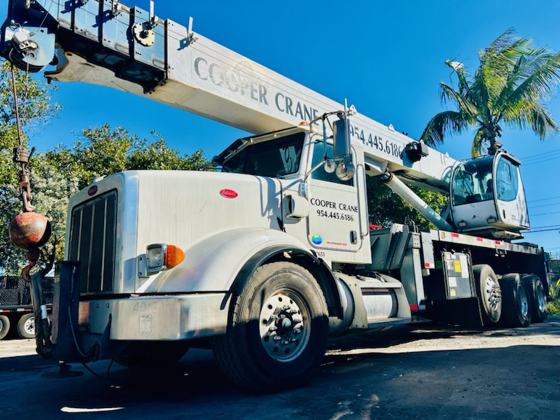 A branded Cooper Crane Peterbilt boom truck set up for a truss lift on a Southeast Florida job site