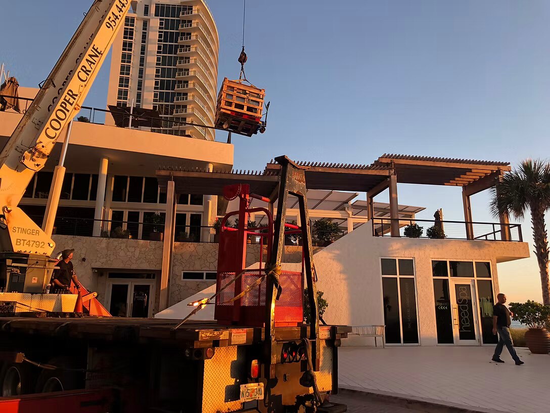 Cooper Crane boom truck setting a unit on the roof of an oceanfront home