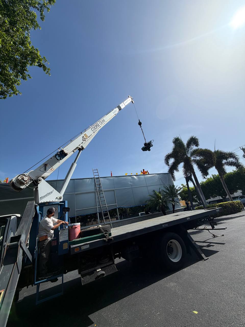 Cooper Crane boom truck hoisting roofing material bundles onto a South Florida roof deck